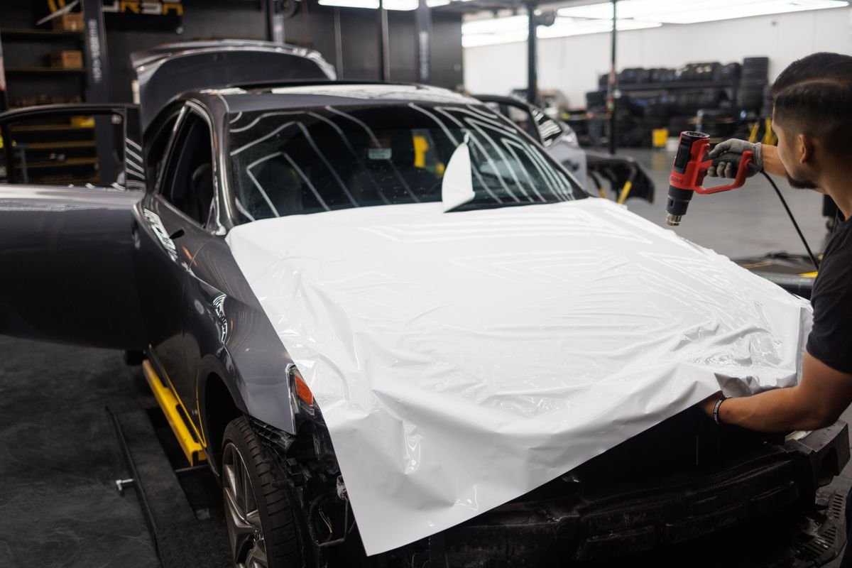 Technician applying paint protection film to a car hood