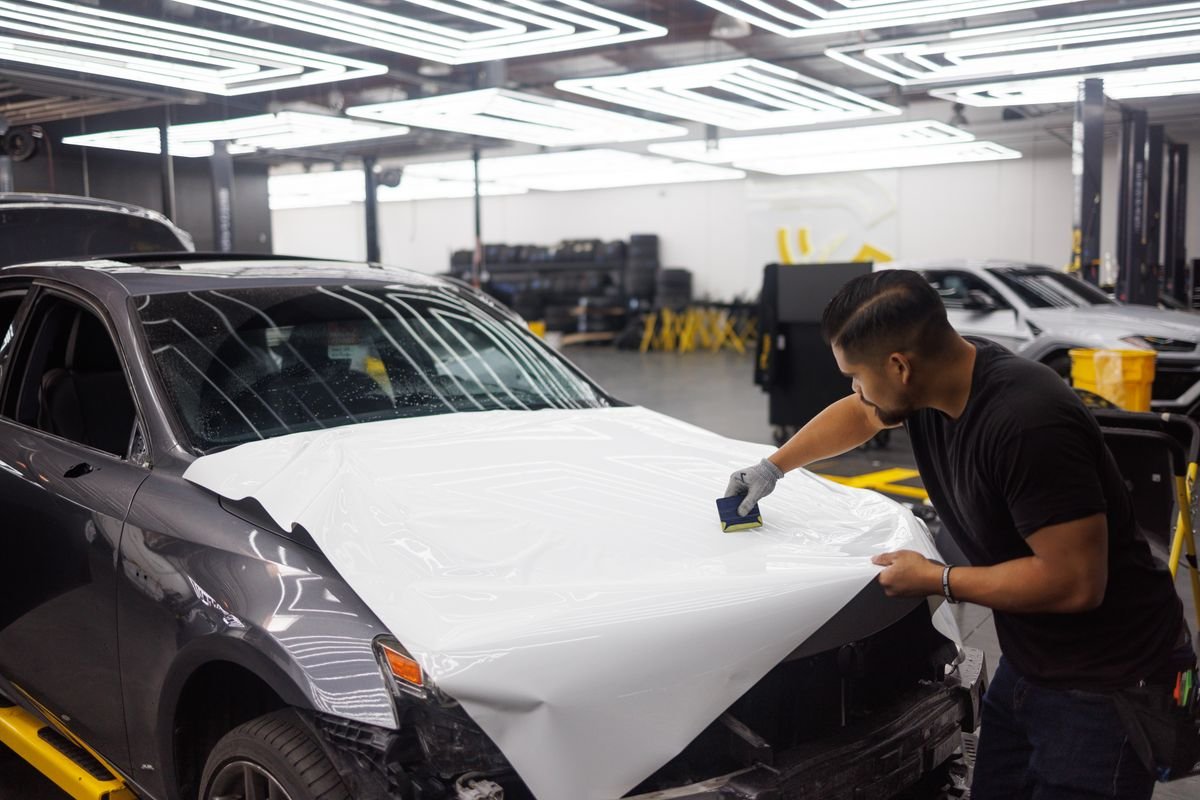Technician applying paint protection film to a car